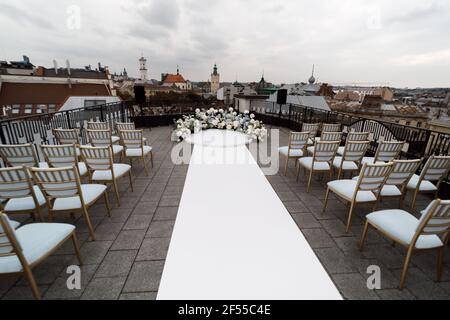 Un endroit merveilleux dans les décorations et les fleurs pour la cérémonie de mariage avec des chaises blanches sur le toit de l'hôtel. Cérémonie de mariage Banque D'Images