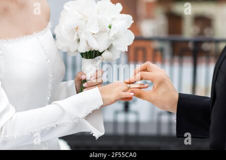 Couple en anneaux d'échange de vêtements de mariage avec un bouquet de fleurs dans l'église. Banque D'Images