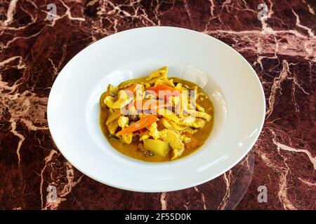 Plat japonais de curry de poulet, en sauce et légumes, dans une assiette sur fond de marbre de pierre. Banque D'Images