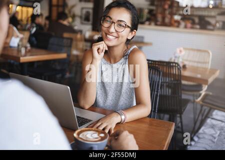 Concept d'entreprise, d'éducation et de personnel. Belle jeune femme orientale avec des cheveux bouclés, porter des lunettes, avoir une réunion décontractée dans le café, boire du café et Banque D'Images