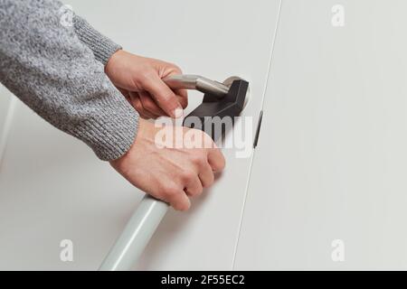 gros plan d'un jeune homme caucasien fixant la porte de sa maison avec une barre de sécurité de blocage de porte Banque D'Images