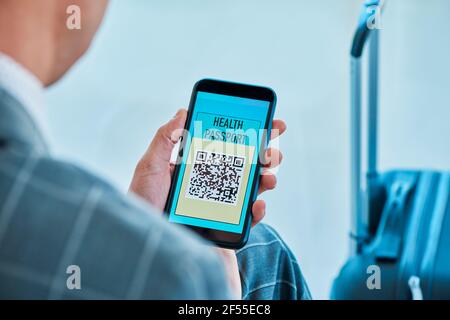 gros plan d'un jeune homme d'affaires caucasien, portant un élégant costume gris, assis dans la salle d'attente d'un aéroport, ayant une simulation de healt électronique Banque D'Images