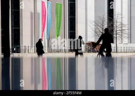 Berlin, Allemagne. 24 mars 2021. Les passants et un cycliste peuvent être vus dans le quartier du gouvernement, avec le paysage reflété dans une dalle de pierre. Credit: Christoph Soeder/dpa/Alay Live News Banque D'Images