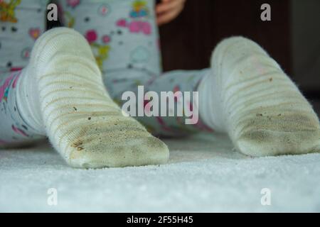 Petite fille debout sur ses genoux dans des chaussettes sales Banque D'Images