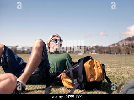 Jeune homme se détendant dans le parc pendant la journée ensoleillée le week-end Banque D'Images