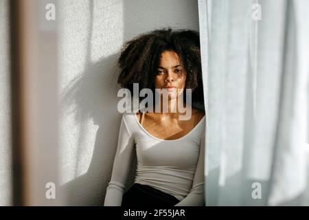 Femme de race mixte debout à la maison contre le mur Banque D'Images