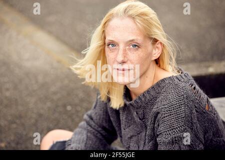 Femme blonde avec des taches de rousseur assis au garage de stationnement Banque D'Images