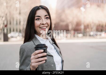 Surprise femme d'affaires tenant une tasse de café en ville Banque D'Images