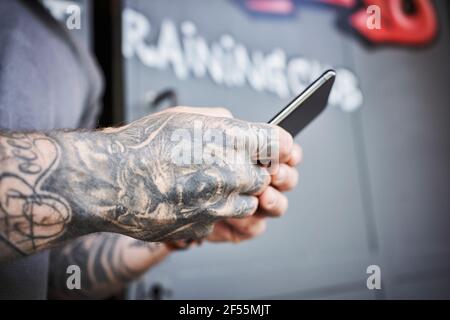 Les mains d'un athlète masculin utilisent un smartphone à l'extérieur de la salle de sport Banque D'Images