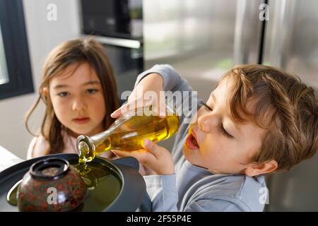 Un adorable garçon souriant verse du jaune d'œuf dans un mixeur de pâte dans la cuisine Banque D'Images