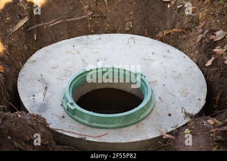 Construction d'une fosse septique. De grands anneaux en béton encastrés dans le sol, depuis le dessus d'une trappe d'égout ouverte, non protégés de la chute par un couvercle. Banque D'Images