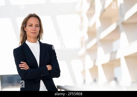 Femme professionnelle assurée debout avec les bras croisés dans le bâtiment de bureau terrasse Banque D'Images