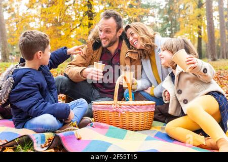 Famille appréciant de prendre un café tout en étant assis ensemble dans la forêt Banque D'Images
