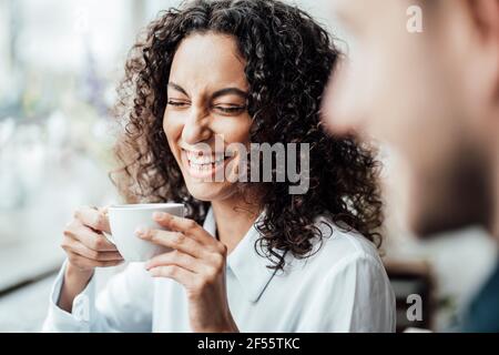 Femme d'affaires gaie prenant un café avec un collègue assis au café Banque D'Images
