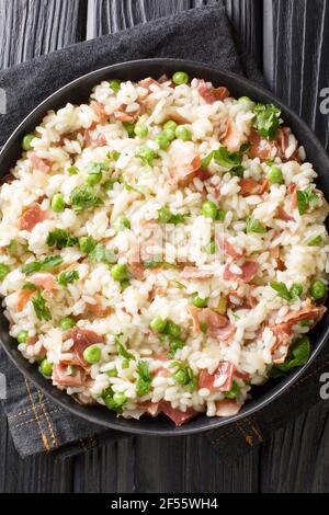 Risi e Bisi cuisine italienne classique de confort de riz avec des petits pois et des morceaux de jambon dans une assiette sur la table. Vue verticale du dessus Banque D'Images