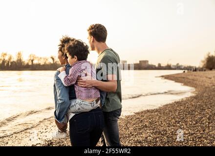 Jeune femme qui soutient le garçon tout en marchant avec l'homme sur le bord du lac Banque D'Images