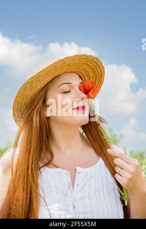 Ukrainienne belle femme dans le champ des coquelicots portrait en plein air. Collectant des coquelicots et des cornflower dans le champ d'été. Symbole de mémoire Poppies en fleurs. Ukrain Banque D'Images
