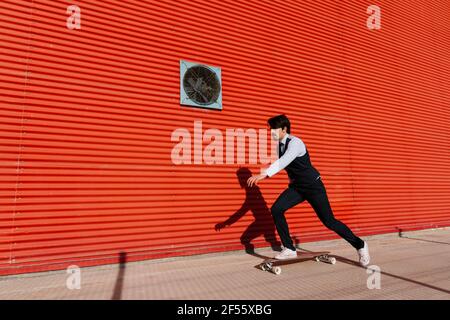 Homme d'affaires avec skateboard sur une longue piste au mur Banque D'Images