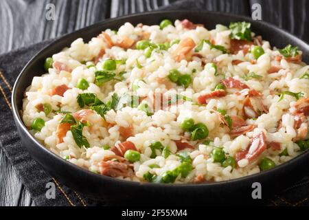 Risotto italien Risi e Bisi fait de riz avec pois et jambon gros plan dans une assiette sur la table. Horizontal Banque D'Images