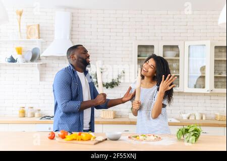 Famille multiethnique dans la cuisine avoir du plaisir, cuisiner ensemble, préparer un plat spécial pour leur anniversaire, danse spontanée et romantisme, les meilleures relations, l'amour sans restriction Banque D'Images