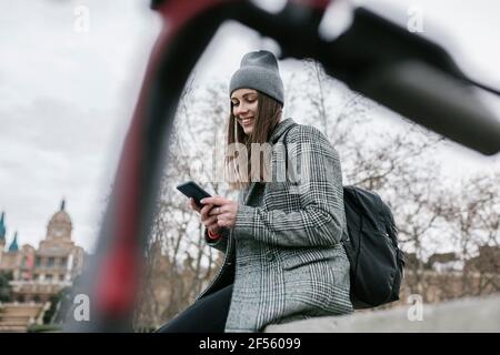 Femme utilisant un smartphone assis sur un mur de retenue ville Banque D'Images