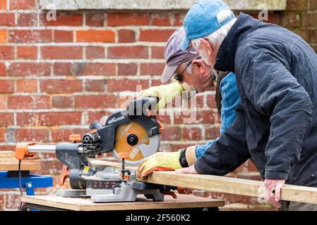 Travailleurs du bois âgés et menuisiers, deux hommes plus âgés coupant du bois avec une scie à hacher circulaire, Alresford, Hampshire, Royaume-Uni Banque D'Images