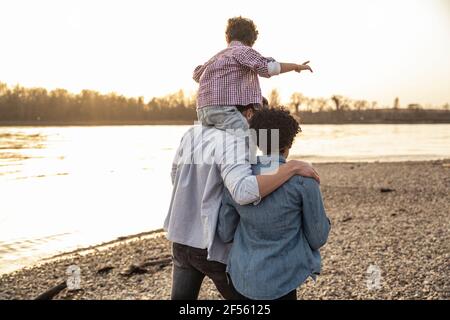 Père portant son fils sur l'épaule tout en marchant par la mère à au bord du lac Banque D'Images