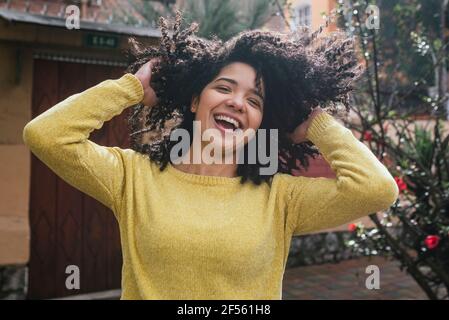 Une femme joyeuse jouant avec des cheveux noirs bouclés dans la cour arrière Banque D'Images