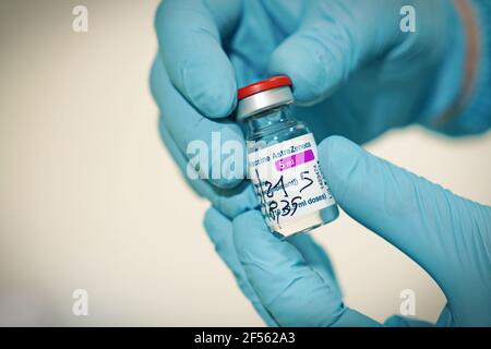 Flacon de vaccin COVID-19 produit par AstraZeneca. La main du médecin dans un gant médical tient une bouteille avec un vaccin coronavirus. Mise au point sélective. Turin, Banque D'Images