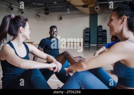 Des athlètes masculins et féminins souriants assis au club de santé Banque D'Images