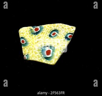 Fragment d'un vaisseau. Une faible courbure du fragment permet l'allocation à un vaisseau, éventuellement à une coque. Dans la technologie Millefiori, Blossom est floraison. À un noyau bleu rouge-blanc se trouvent dans une double rangée de pétales jaunes, qui sont entourés de blanc. Pour la production, des verres de différentes couleurs ont été façonnés sur des tubes et des tiges. Elles étaient comprimées et chauffées, ce qui entraînait une longue barre. Le ​​now en verre tranché avait une grande variété de motifs amorphes ou floraux. Par la suite, plusieurs de ces plaquettes ont été repliées ensemble, réchauffées à nouveau et pressées en forme vasculaire. Burry pour la proce de fabrication élaborée Banque D'Images