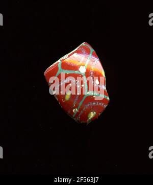 Fragment d'un vaisseau. Une faible courbure du fragment de verre permet l'affectation à un vaisseau, éventuellement à une coque. Le revêtement de cisaillement rouge lignes turquoise. Dans chaque nid d'abeille, un ornement floral en technologie Millefiori peut être vu. Chaque fleur se compose d'un noyau jaune avec contour turquoise, qui attire avec une légère distance avec une double ligne de cercle blanc, dont l'espace est rempli de points blancs, qui sont séparés par des traits blancs. Pour la production, des verres de différentes couleurs ont été formés en tubes et en tiges. Elles étaient comprimées et chauffées, ce qui entraînait une longue barre. Le verre coupé en tranches de ​​now avait de la diffuse Banque D'Images