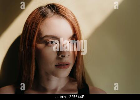 Femme à tête rouge envisagée contre le mur Banque D'Images