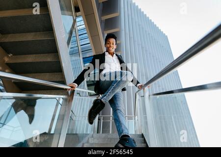 Un homme souriant dansait sur un escalier contre le bâtiment Banque D'Images