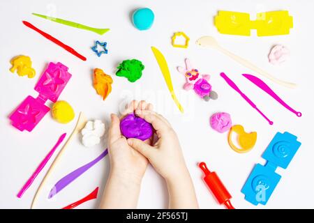Les enfants jouent avec de l'argile à modeler colorée sur fond blanc. Jeu éducatif avec argile. Enfants sculptant des figures d'argile. Develo tôt Banque D'Images