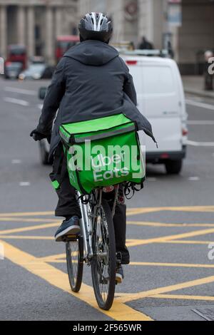 Londres, Royaume-Uni. 24 mars 2021. Un passager Uber Eats traverse la City de Londres. Deliveroo, concurrent, se prépare à une cotation boursière de 8,8 milliards de livres sterling le 7 avril, mais certains commentateurs ont souligné le risque d'investissement selon lequel les livreseurs ne sont pas classés comme des employés, de sorte qu'ils n'ont pas le droit à un salaire minimum, à des congés ou à des congés de maladie. Les participants les plus actifs de l’entreprise recevront des bonus pouvant atteindre 10,000 £ après l’introduction en bourse. Credit: Stephen Chung / Alamy Live News Banque D'Images