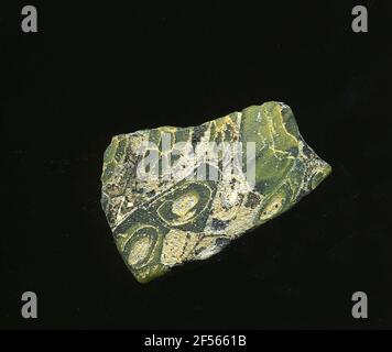 Fragment de mosaïque de verre. Le petit fragment de verre montre la raison verte de plusieurs fleurs dans la technologie millefiori. Ils se composent de spirales jaunes ou de cercles avec contour jaune, qui sont composés à des fleurs. À l'époque romaine, ils utilisaient du verre coloré et ornementé pour les navires, les mosaïques, les décorations murales et les ornements de meubles. Banque D'Images