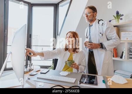 Les médecins prenant un café tout en travaillant sur ordinateur à la clinique Banque D'Images