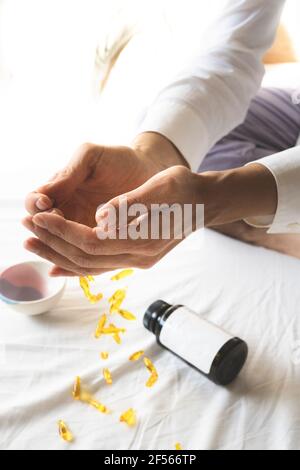 Les mains de la femme au-dessus des pilules de vitamines tombant sur le lit Banque D'Images