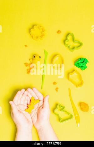 Les enfants jouent avec de l'argile à modeler colorée sur fond jaune. Jeu éducatif avec argile. Enfants sculptant des figures d'argile. Devel Banque D'Images