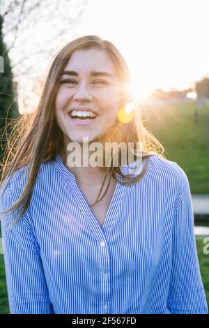 Femme joyeuse debout au parc pendant le coucher du soleil Banque D'Images