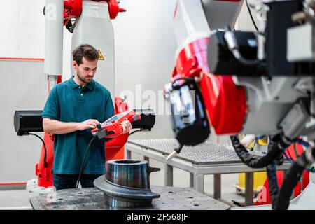 Un ingénieur travaillant en robotique via le contrôle en usine Banque D'Images