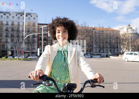 Jeune femme afro avec vélo électrique en ville Banque D'Images