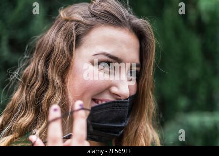 Jeune femme qui prend un masque de protection Banque D'Images