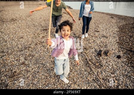 Garçon joueur tenant des bâtons tout en jouant avec les parents en arrière-plan sur galet Banque D'Images