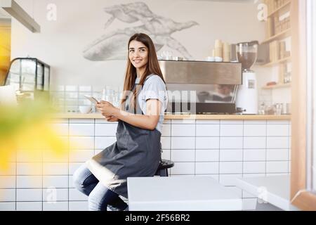 Portrait d'une jeune femme maître de café débutant sa journée par un réseau social dans un caffee brillant. Le barista est son travail de rêve. Banque D'Images