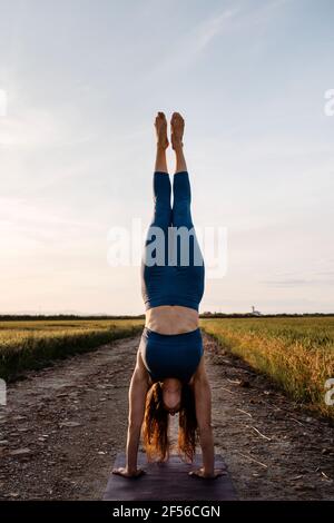 Femme faisant la main contre le ciel sur la route Banque D'Images