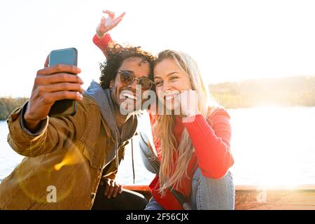 Homme prenant le selfie avec une femme par téléphone portable tout en étant assis en canoë sur la rivière Banque D'Images