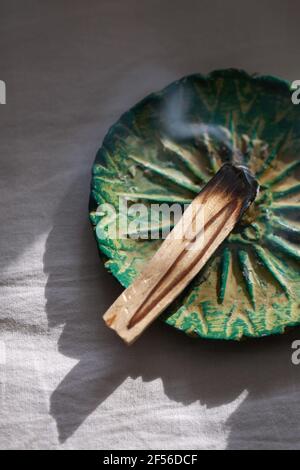 Bâton de palo santo brûlé sur plaque de céramique. Concept rituel antistress et relaxation Banque D'Images