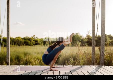 Femme forte faisant Tittibhasana pose de yoga au belvédère Banque D'Images